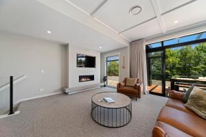 uma sala de estar com um sofá, uma mesa e uma lareira em Lake Luxe - Taupo em Taupo
