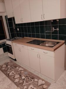 uma cozinha com lavatório e algumas sandálias no chão em Forrás-hegyi Apartman em Felsőörs