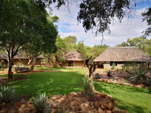 a house with a thatched roof in a yard at Boulders Safari Lodge in Malelane