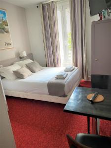 a bedroom with a bed and a table with a remote control at Hôtel du Parc Montsouris in Paris