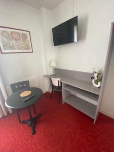 a room with a desk and a table and a tv at Hôtel du Parc Montsouris in Paris