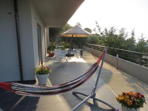 a hammock on a balcony with an umbrella at La Casa del Riccio in Tindari