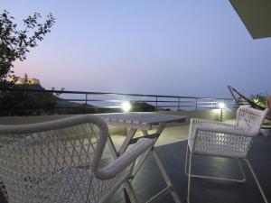 a table and chairs on a balcony at night at La Casa del Riccio in Tindari
