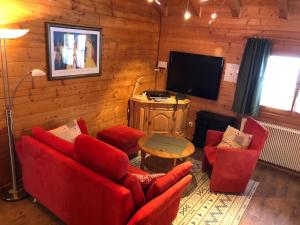 a living room with red furniture and a flat screen tv at Blockhaus Noffke in Stamsried