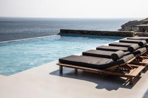 a row of chaise lounges next to the ocean at Nimbus My Aktis in Super Paradise Beach