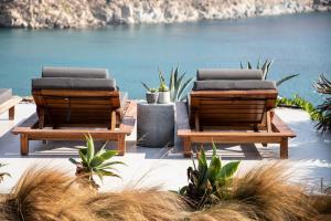 two lounge chairs sitting next to a body of water at Nimbus My Aktis in Super Paradise Beach