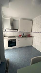 una cocina con armarios blancos y fregadero en Apartamento Islas Malvinas 39, en Vecindario