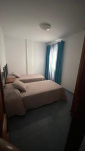 2 letti in una camera da letto con tende blu di Apartamento Islas Malvinas 39 a Vecindario