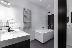 a white bathroom with a tub and a sink at Apartamenty Zakopane Krupówki in Zakopane