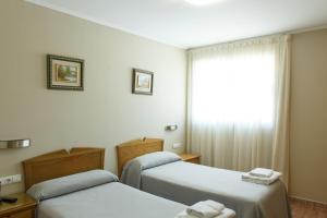a hotel room with two beds and a window at La Orza de Angel in Chiva