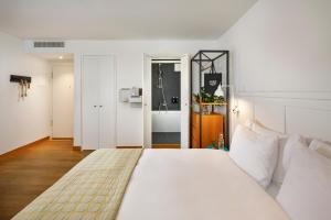 a bedroom with a large white bed and a bathroom at Marktgasse Hotel in Zürich