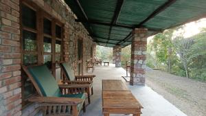 a porch of a brick building with wooden benches at Wild Brook in Rishīkesh