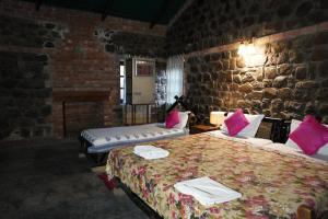 a room with two beds and a stone wall at Wild Brook in Rishīkesh