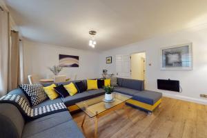 sala de estar con sofá azul y almohadas amarillas en Park Lane Apartments - Clarges Street en Londres