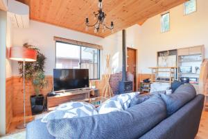 a living room with a blue couch and a tv at Ocean View House in Atami