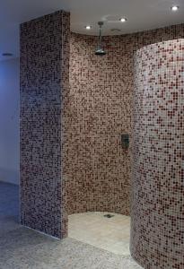 Łazienka z wyłożoną kafelkami ścianą z prysznicem w obiekcie Aismares Hostel w Kłajpedzie