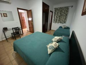 1 dormitorio con 2 camas y mesa con silla en Hostal Mellizo, en Lebrija