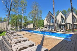 a pool with lounge chairs and a house at Čiki Puki Purslai in Palanga