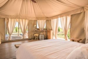 a bedroom with a bed and a large window at Terme di Vulci Glamping & Spa in Canino