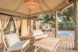 a deck with chairs and a table and a tent at Terme di Vulci Glamping & Spa in Canino