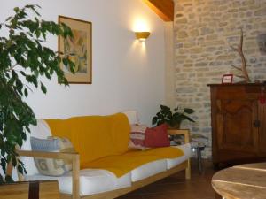 a yellow couch in a living room with a brick wall at Chambre d'Hôtes La Bourdasse in Loubens