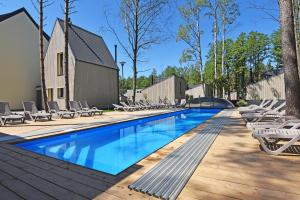 a swimming pool with lounge chairs on a wooden deck at Čiki Puki Purslai in Palanga