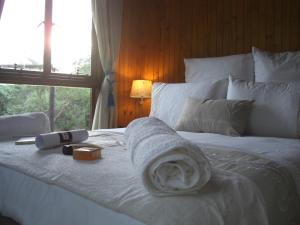 uma cama branca com uma toalha e uma janela em Blyde River Cabins em Hoedspruit