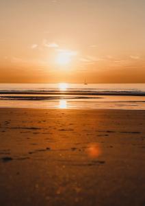 - un coucher de soleil sur la plage avec un bateau dans l'eau dans l'établissement relax @the beach, au Coq