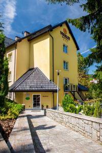 a large yellow building with a sign on it at Hotel Vivaldi in Karpacz