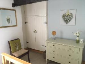 a bedroom with a white dresser and a chair at 200 year old Gardener's cottage, Mid Wales in Llanidloes