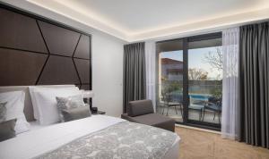 a bedroom with a bed and a chair and a balcony at Ellure Luxury Suites in Split