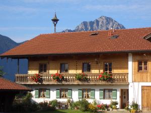 a house with flowers on the balcony with a mountain in the background at Huberbauernhof Ferienwohnungen in Piding