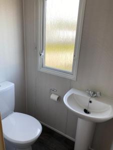 La salle de bains est pourvue de toilettes, d'un lavabo et d'une fenêtre. dans l'établissement Camping De Koehoorn, à Meliskerke