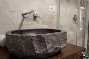 ein Steinwaschbecken im Bad mit Dusche in der Unterkunft TIK TAK B&B diffuso in Verbicaro