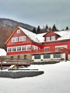 un grande edificio rosso con neve per terra di Bartlova bouda a Weissbach