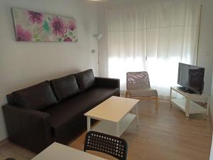 a living room with a black couch and a tv at El Jardin BeNerja in Nerja