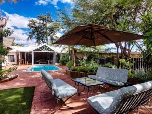 a patio with an umbrella and chairs and a pool at Londiningi Guesthouse in Windhoek