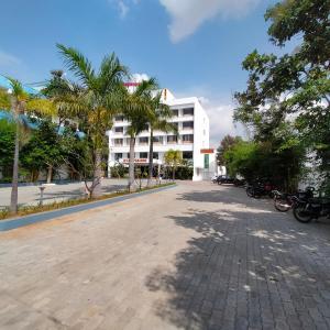 una calle frente a un edificio con palmeras en JB Residency, en Tiruchchirāppalli