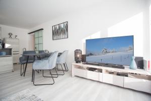 ein Wohnzimmer mit einem TV, einem Tisch und Stühlen in der Unterkunft Astenperle II in Winterberg Infrarosauna, Massagesessel, Balkon in Winterberg