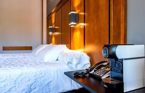 a hotel room with a bed and a desk with a phone at Hotel Condestable Iranzo in Jaén