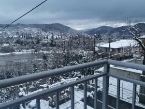 a snow covered balcony with a view of a city at Guesthouse LUKA in Kutaisi