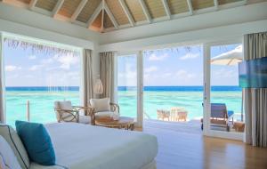 Baglioni Resort Maldives - Luxury All Inclusive في دالو أتول: غرفة نوم مع سرير وإطلالة على المحيط