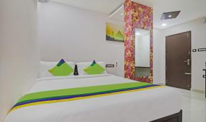 a bedroom with a white bed with green and yellow stripes at Treebo Trend J A Royal Suites Manikonda in Hyderabad