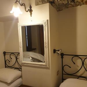 1 dormitorio con 2 camas y espejo en la pared en Appartamento Dimora in Piazza -Locazione Turistica Santa Maria Maggiore, en Santa Maria Maggiore