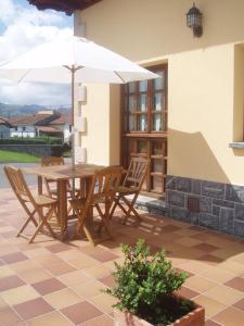 a wooden table and chairs with an umbrella on a patio at Hotelapartamentos Torres in Selorio +17 photos