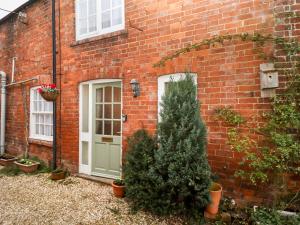 ein Backsteinhaus mit grüner Tür und zwei Weihnachtsbäumen in der Unterkunft 5A Waterfall Way in Market Harborough