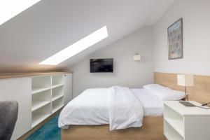 a white bedroom with a bed and a desk at Aparthotel Esencja Warszawy Nowy Świat in Warsaw