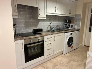 a kitchen with white cabinets and a washer and dryer at 18 The Mullins in Donegal