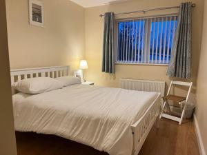 a bedroom with a large white bed and a window at 18 The Mullins in Donegal