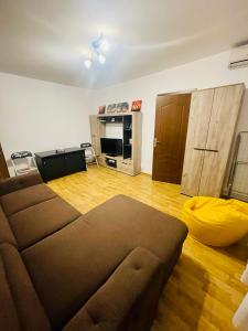 ein Wohnzimmer mit einem braunen Sofa und Holzboden in der Unterkunft Joy City Stay Angela Sava 6 in Timişoara